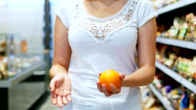 女人的手在超市里慢动作地抛出五颜六色的橙色