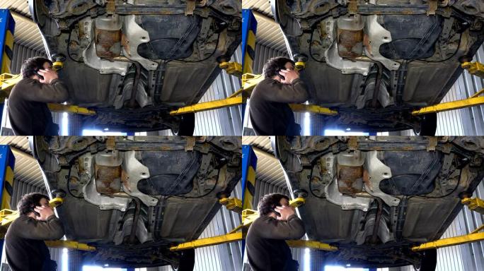 机械师用电话修理生锈的排气系统。