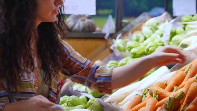 漂亮的年轻漂亮的女孩或女人在市场上购买食物，挑选胡萝卜女孩在超市购物，购买食物。