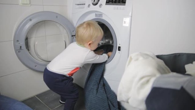 两岁的孩子做家务。装载洗衣机。