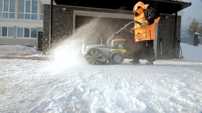 男子在冬天用扫地机清理院子里的雪