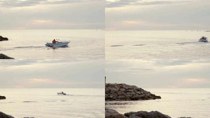充气船在太阳低的平坦海面上日出或日落时离开小港口