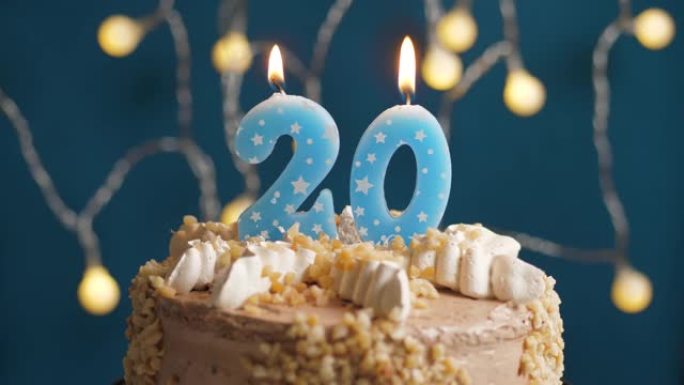 蓝色背景上有20号蜡烛的生日蛋糕。蜡烛吹灭了。慢动作和特写视图