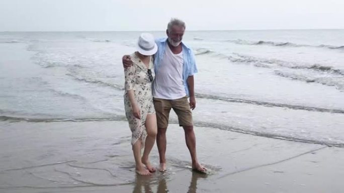 活跃的老年人夫妇在海滩上散步和微笑