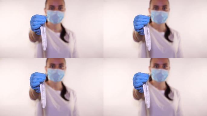 医生戴着蓝色手套的手拿着一个用过的避孕套，白色背景上有精子。精子乳胶和防止怀孕
