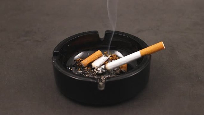 黑色烟灰缸中的香烟，烟头冒烟
