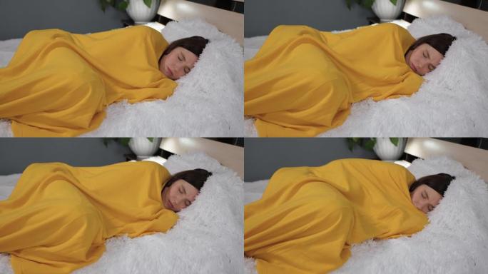 女孩躺在床上，裹着黄色格子，她摇晃并冻结了身体。感冒，流感，病毒，急性呼吸道疾病，发热，寒战概念。慢