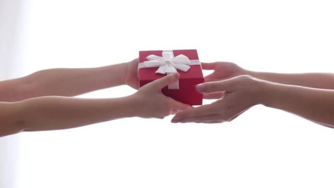 一个孩子在一个带有白色蝴蝶结的红色盒子里给妈妈一个小礼物