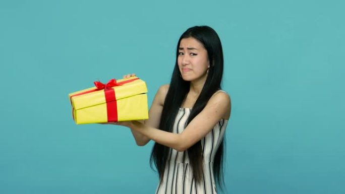 对现在不满。不快乐的亚洲女人，长发窥视着盒子，对礼物感到失望