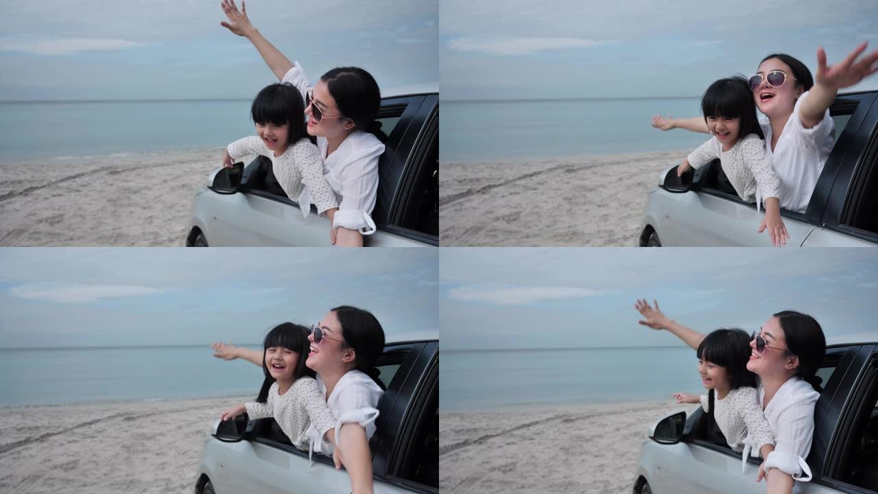 暑假快乐的亚洲家庭母亲和女儿张开双臂在海滩上一起坐汽车飞行。假日和汽车旅行概念。慢动作