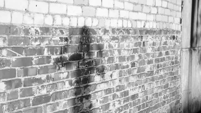 日落时，一个年轻女孩在肮脏的砖墙附近跳舞的影子剪影。黑白视频。慢动作
