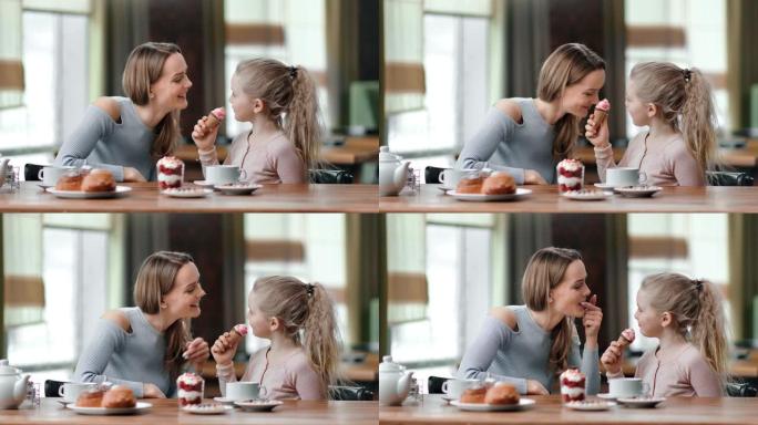 快乐的母女俩在咖啡馆一起吃甜点。红色相机上的中等镜头