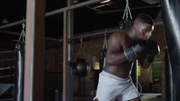 年轻，健康的非裔美国人在MMA健身房击中沉重的包
