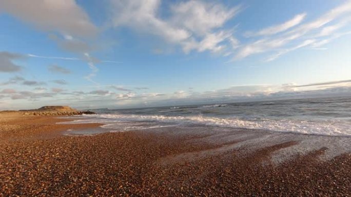在雄伟的蓝天白云下，石质海滩上海浪撞击的慢动作 (120 fps) 镜头