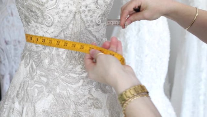 时装设计师在人体模型上测量婚纱