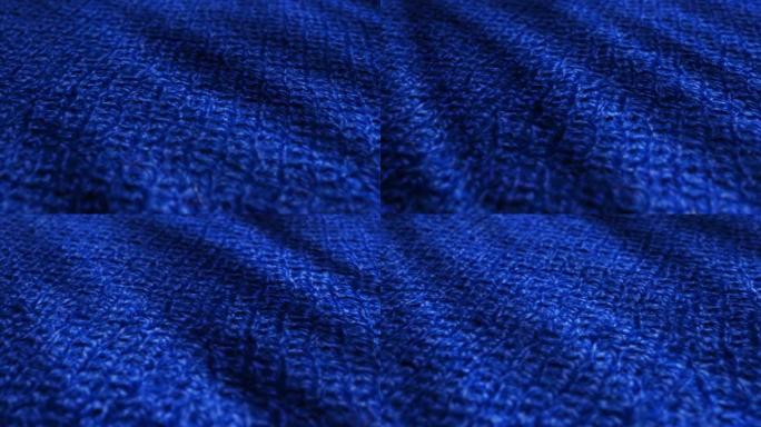 蓝色针织羊毛，套头衫面料是挥舞的背景。特写，纤维毛衣的宏观拍摄