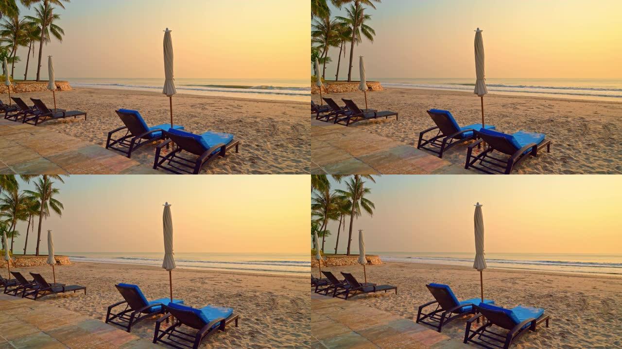 太阳伞椅海滩与棕榈树和海洋海滩在日出时间