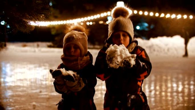 两个小孩站在溜冰场上，向空中扔雪