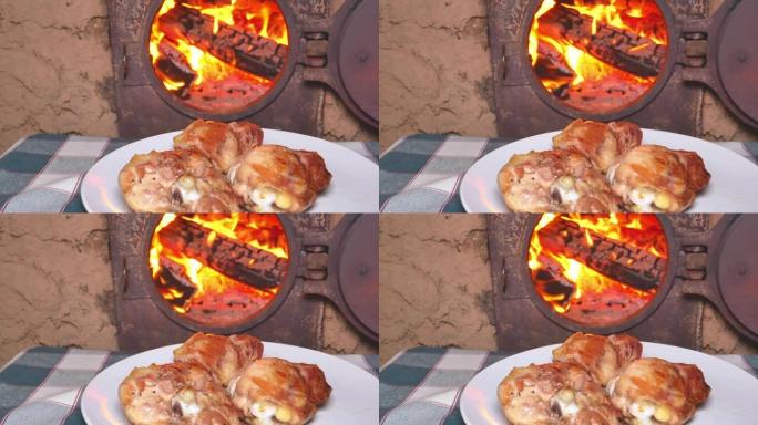 在燃烧的火炉背景下的盘子里烤肉鸡肉。烧木头的炉子。火焰。肉类菜肴。菜单。食物视频。