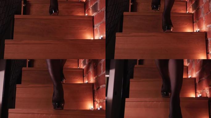 性感的女性双腿穿着高跟鞋走下楼梯特写。蜡烛的浪漫气氛。