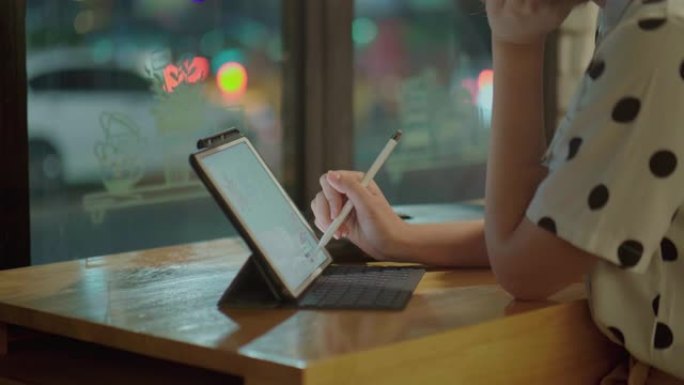亚洲自由职业者女性晚上在咖啡馆使用笔记本电脑