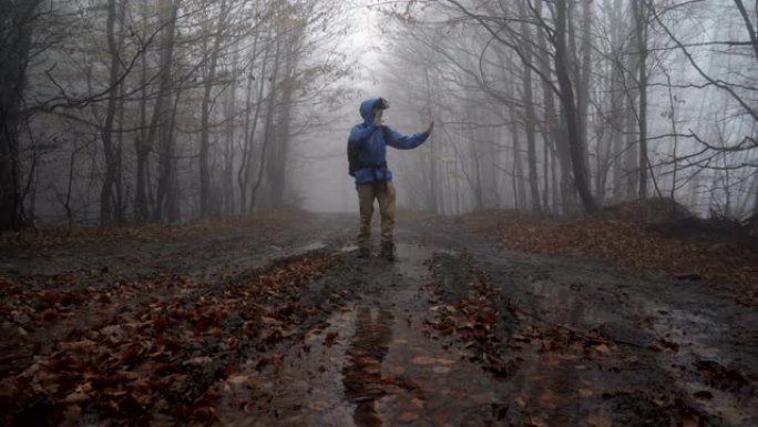 男子在雾蒙蒙的阴雨森林户外玩VR眼镜游戏，四处游荡