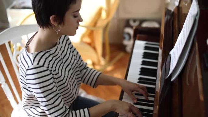 年轻女钢琴家在家中的房间里弹钢琴