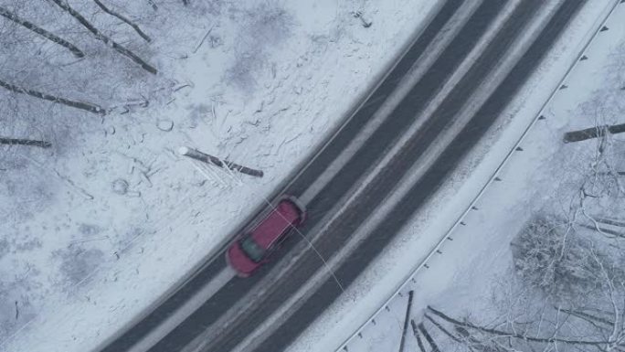 在降雪下驾驶高速公路穿过森林的汽车。无人机俯视航拍视频。