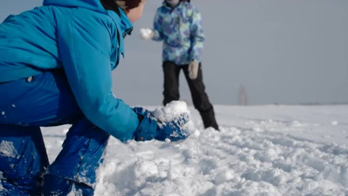 户外家庭冬季乐趣。母亲和儿子打雪仗。慢动作。