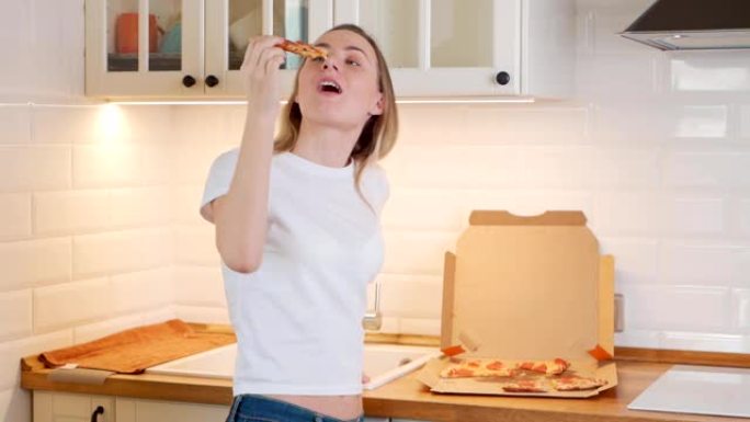 快乐的年轻女子在家吃一片热披萨
