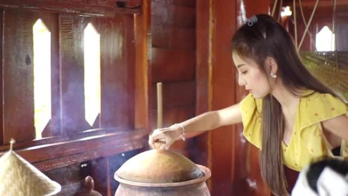 一位年轻的亚洲妇女在传统厨房准备泰国菜。