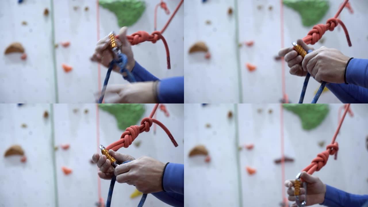 人在室内学习和练习在攀岩墙附近打结。用登山扣准备攀爬的护栏线