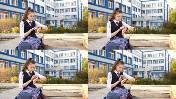 十几岁的女孩背着背包坐在学院附近的栏杆上，看着他的智能手表。