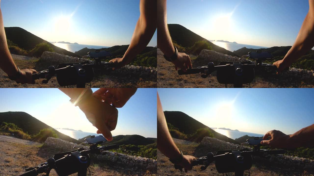 POV拍摄运动员骑自行车的男子骑自行车在ponza岛在日落到达和检查智能手机。