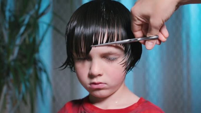 理发时心烦意乱的男孩。理发师用梳子梳头。