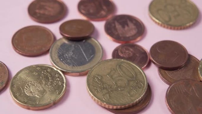 粉红色背景上的欧元硬币和美分