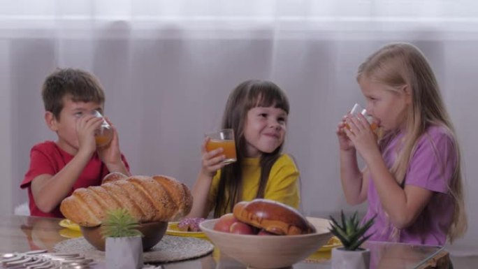 甜蜜的餐桌，有趣的孩子们在庆祝儿童派对的活跃游戏后咬一口喝果汁