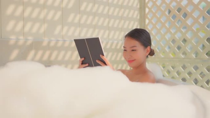 年轻的亚洲女性在浴缸里看书放松
