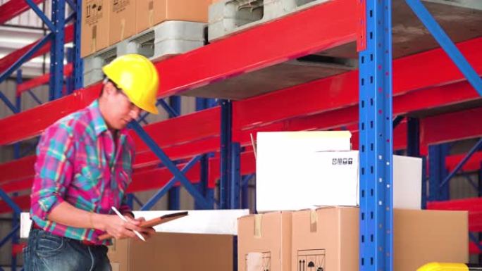 亚洲男子工头看着纸盒，在仓库的盒子里托运货物
