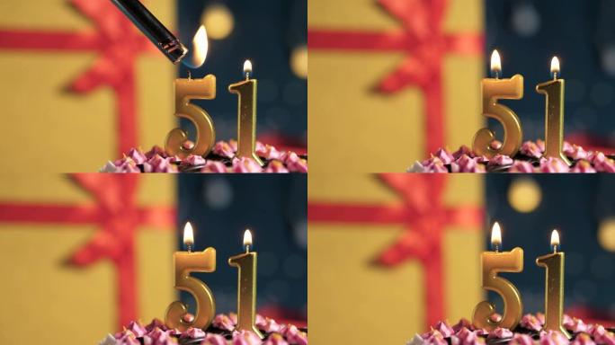 生日蛋糕编号51点灯燃烧的金色蜡烛，蓝色背景礼物黄色盒子用红丝带绑起来。特写和慢动作