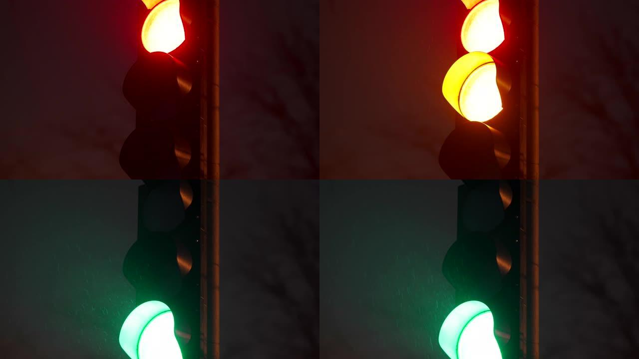 夜间城市街道特写处的红色黄绿色交通信号灯。