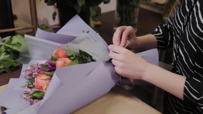 专业花店将花束与丝绸丝带联系在一起。国际妇女节的美丽花束