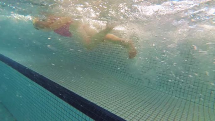 水下少女在游泳池慢动作游泳