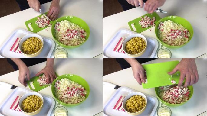 一个男人做沙拉。将螃蟹切成薄片，粘在砧板上，然后放入切碎的北京白菜容器中。在其他容器中，玉米和蛋黄酱