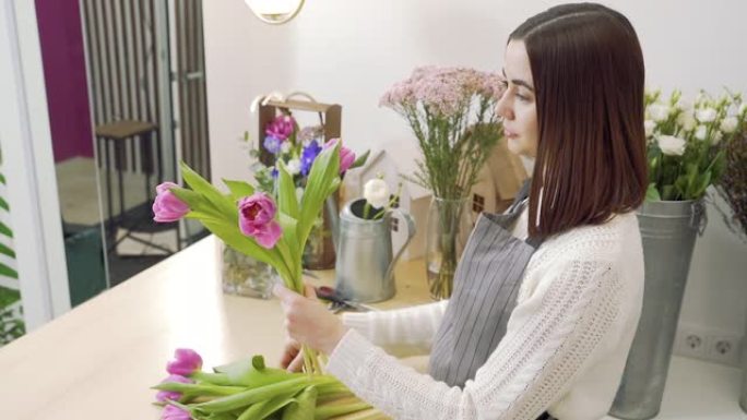 年轻的女花店在花店或车间里组成一束郁金香