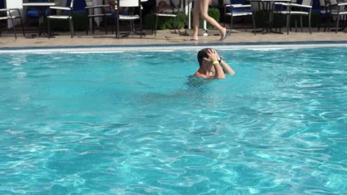 男子在水下游泳，从游泳池的水中浮出水面