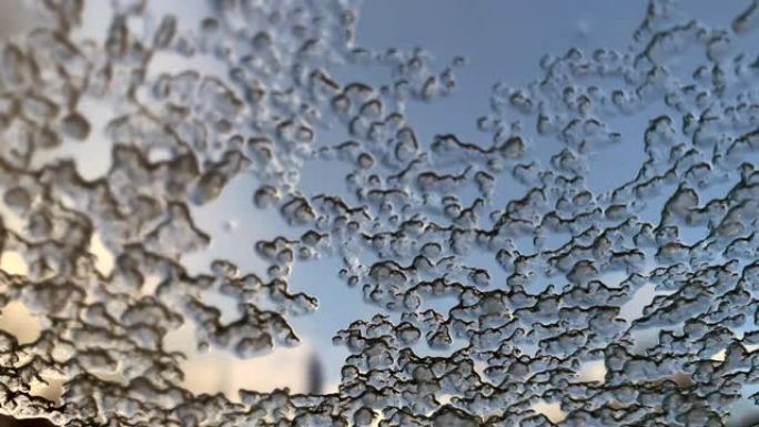 湿冰落在汽车的湿玻璃上，水和雪花流下来