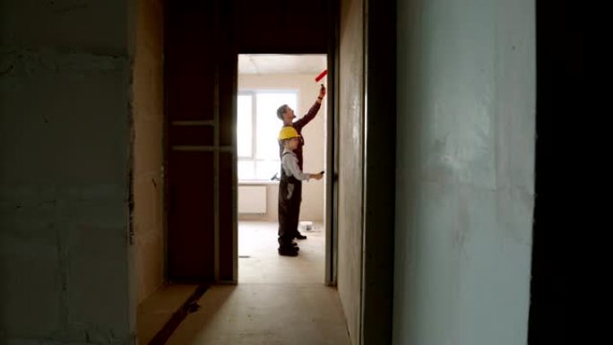 在白天修理草稿公寓-小男孩和他的父亲在房间内粉刷墙壁