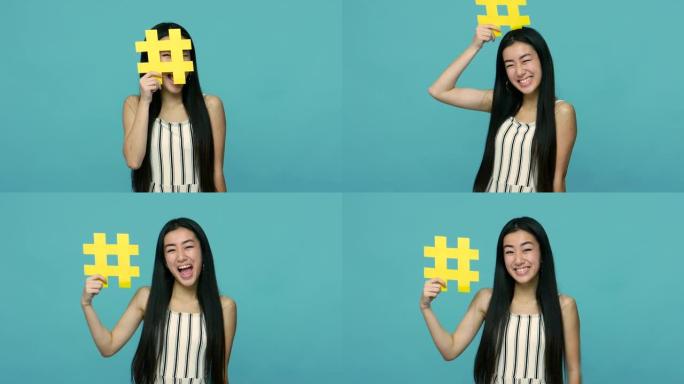 可爱的快乐亚洲女人，留着长长的黑发，拿着黄色的标签符号，跟随互联网趋势的哈希标志