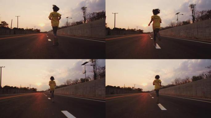 小女孩在日落时在路上奔跑